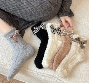 Detail of coral fleece socks featuring classic plaid bow knots in various warm colors