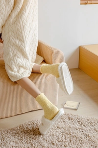 Dettaglio di morbide calze in pile corallo giallo con pantofole in peluche bianco