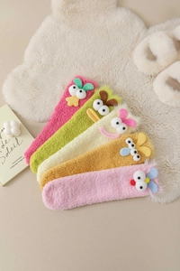 Close-up of five colorful plush cartoon headbands in soft fleece on a cozy carpet