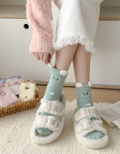 Detail of coral fleece cartoon socks with plush buckled slippers on warm wood floor