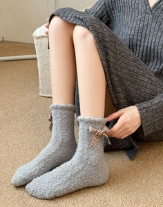 Close-up of thick grey coral fleece socks with checkered bow detail and soft elastic cuffs