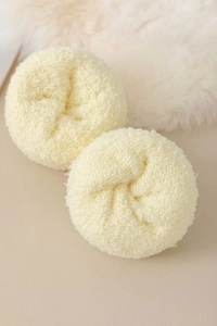 Detail of two plush cream-white fuzzy hair scrunchies with soft faux fur texture