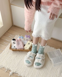 Detail of plush coral fleece animal socks with 3D ears and embroidery on wooden floor