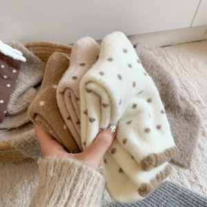 Gros plan de chaussettes en peluche à pois aux tons terreux et texture douce tricotée