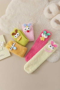 Flat lay of five colorful thickened coral fleece cartoon socks on a soft plush rug
