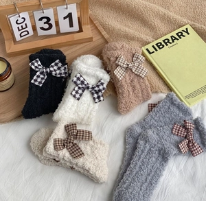 Detail showing plush coral fleece socks with houndstooth bowknots in neutral colors