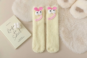Close-up of yellow fuzzy coral fleece socks with 3D cartoon eyes and heart details