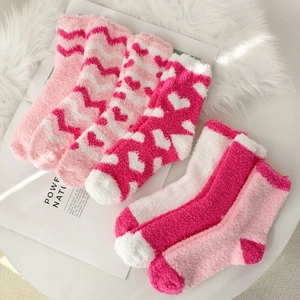Close-up of pink and white coral fleece heart-patterned socks on white fur