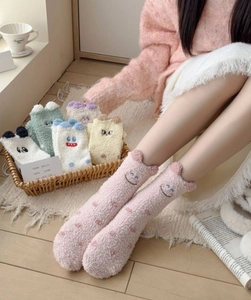 Detailed view of cozy coral fleece socks with 3D animal ears in warm indoor setting