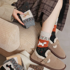 Détail de chaussettes en tricot avec motifs de chiot blanc et sapin aux tons d'automne