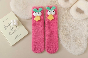 Detail of pink coral fleece socks featuring a 3D cartoon duck doll in a cozy home setting