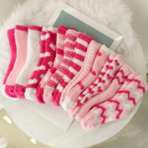 Detail of soft coral fleece socks in pink and white with heart patterns for winter