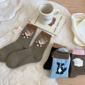 Detail of thick wool socks with cute 3D cartoon animal patterns on a cozy white rug