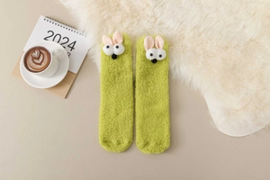Close-up of fluffy green coral fleece warm socks with cute 3D bunny ears and 2024 calendar