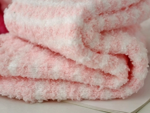 Close-up of soft coral fleece material with pink and white stripes for plush winter socks