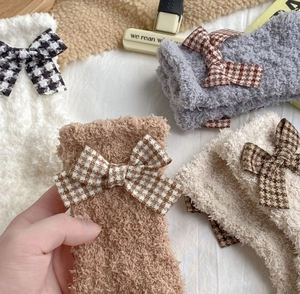 Detailed texture of thick coral fleece winter socks with houndstooth bow accents