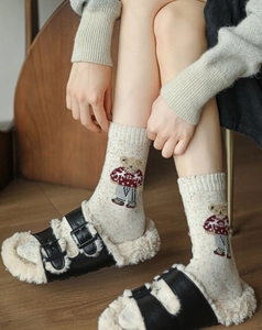 Detailed close-up of oatmeal knit socks with cute bear embroidery and colorful flecks