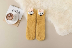 Close-up of fluffy yellow thermal coral fleece socks with cute cartoon eyes and rabbit ears