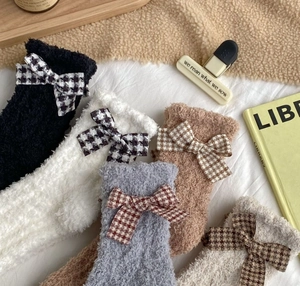Detail of coral fleece winter socks with houndstooth bows in warm home setting