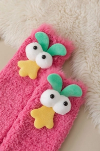 Close-up of thick pink coral fleece socks with 3D cartoon eyes on warm plush background