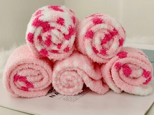 Close-up of rolled coral fleece socks with pink leopard pattern in a stacked arrangement