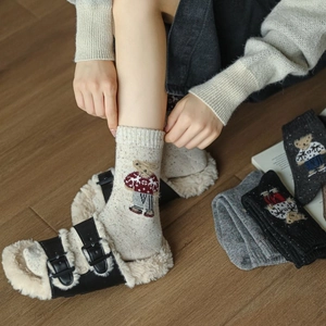 Detail of warm winter socks with cute teddy bear embroidery and textured tweed knit fabric