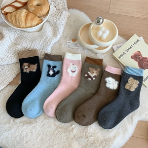 Detailed set of six wool socks with cute animal embroidery on soft white carpet