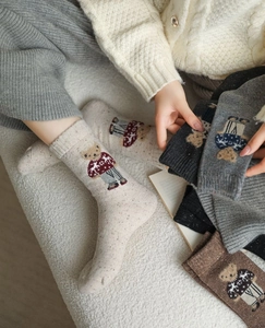 Detailed close-up of thick knit crew socks featuring cute embroidered bear patterns