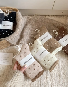 Gros plan de chaussettes en peluche à pois épais aux tons terre avec emballage
