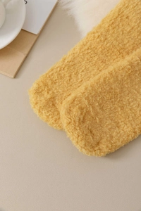 Close-up of thick ginger yellow coral fleece socks with warm fluffy texture for winter