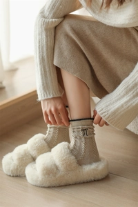 Detailed view of cable knit wool socks with black bow embroidery and plush slippers