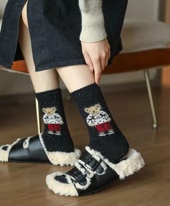 Close-up of black speckled knit socks featuring a detailed knitted cartoon bear design