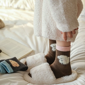 Close-up of cozy wool socks with cute puppy motif and matching plush slippers on a bed