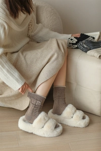 Close-up of cable knit wool socks and plush slippers in a cozy lifestyle setting
