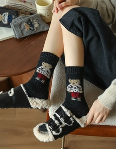 Detail of black knit crew socks featuring a cute plush bear embroidery and ribbed texture