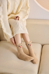 Nahaufnahme warmer beige Korallenvlies-Socken mit süßen 3D-Ohren und Bestickung
