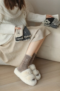 Detail of wool knit socks with cable pattern, ruffle cuff, and bow embroidery