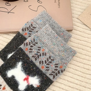 Gros plan de chaussettes d'hiver en tricot épais avec motif de terrier blanc et revers gris