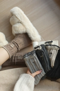 Detail of winter wool socks featuring cable knit patterns and delicate side bow accents