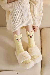 Detail von gelben Korallenfleece-Socken mit 3D-Bärenohren und Stickerei für den Winter