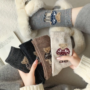 Close-up of cozy knitted crew socks with cute teddy bear patterns in various colors