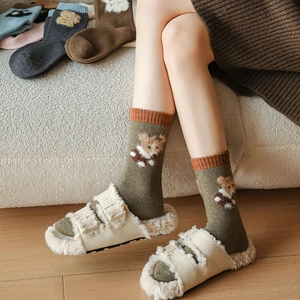 Detailed view of thick wool socks with teddy bear embroidery in a cozy home setting