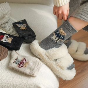 Detailed close-up of thick knitted winter socks featuring an embroidered bear pattern