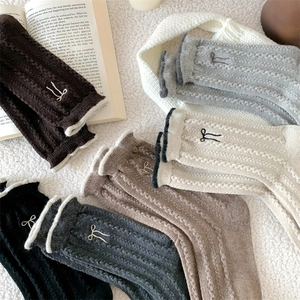 Detailed view of cable knit wool socks with bow embroidery and ribbed cuffs
