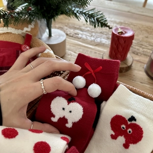 Red Christmas knit socks with pom-poms and apple patterns in a cozy festive basket