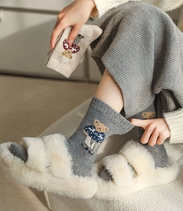 Detail of gray knitted socks featuring a cute bear pattern and colorful dot yarn texture