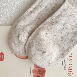 Close-up of speckled knit wool socks with soft texture on a lifestyle magazine background