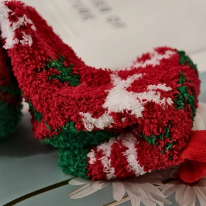 Close-up of soft coral fleece Christmas socks featuring festive reindeer and snowflake patterns