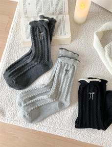 Detail of wool cable knit socks with lace edge and delicate bow embroidery
