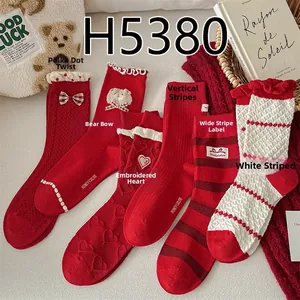 Detail view of red and beige winter socks with bow tie, heart, and bear embroidery designs